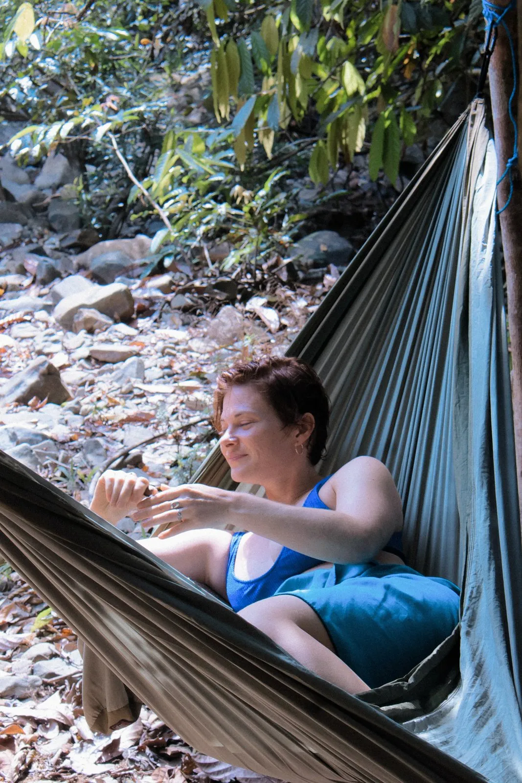Person relaxing in a hammock by the water
