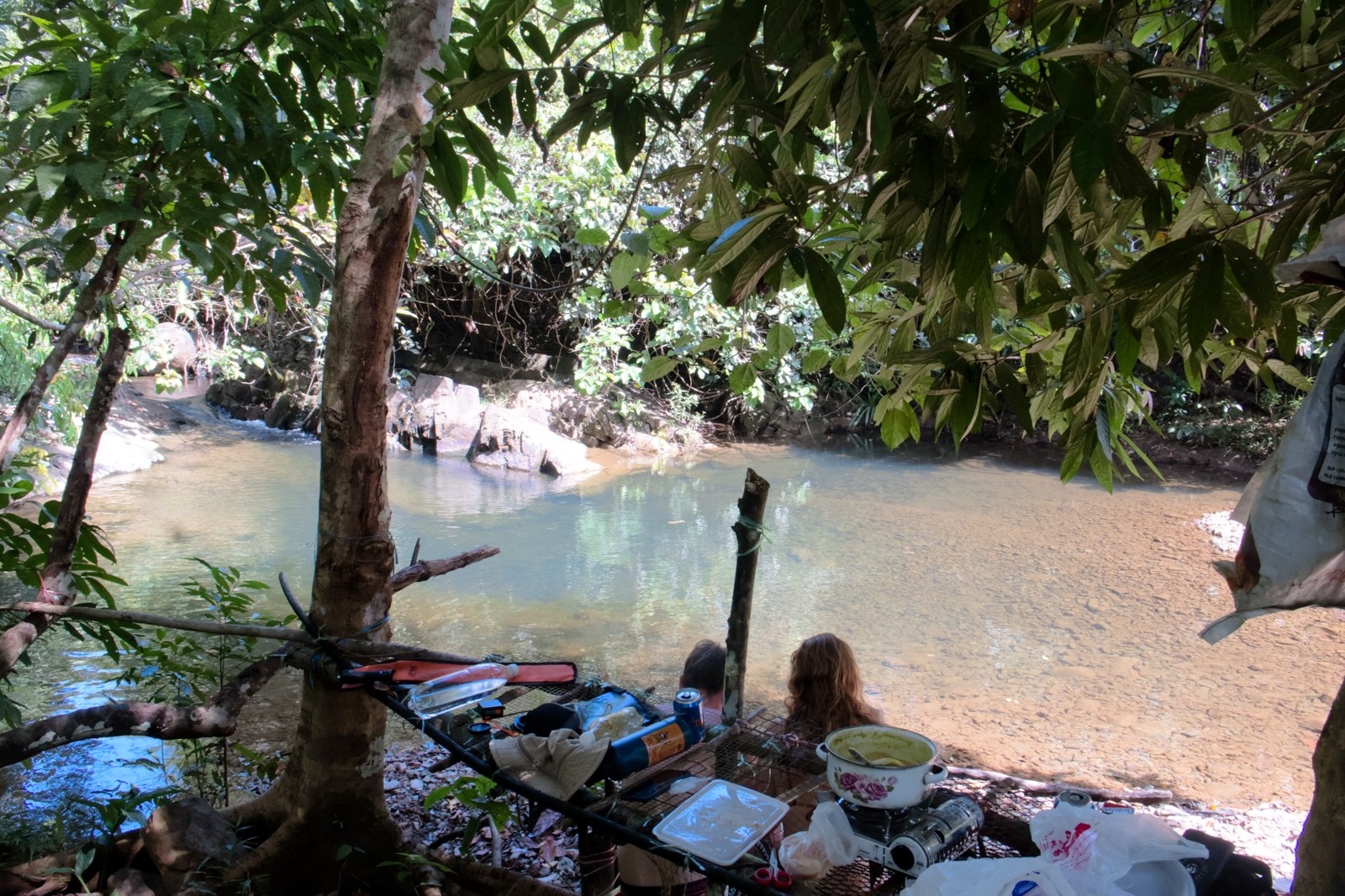 The Jungle Bar — handmade table by the water with cooking pot and view of the freshwater pool