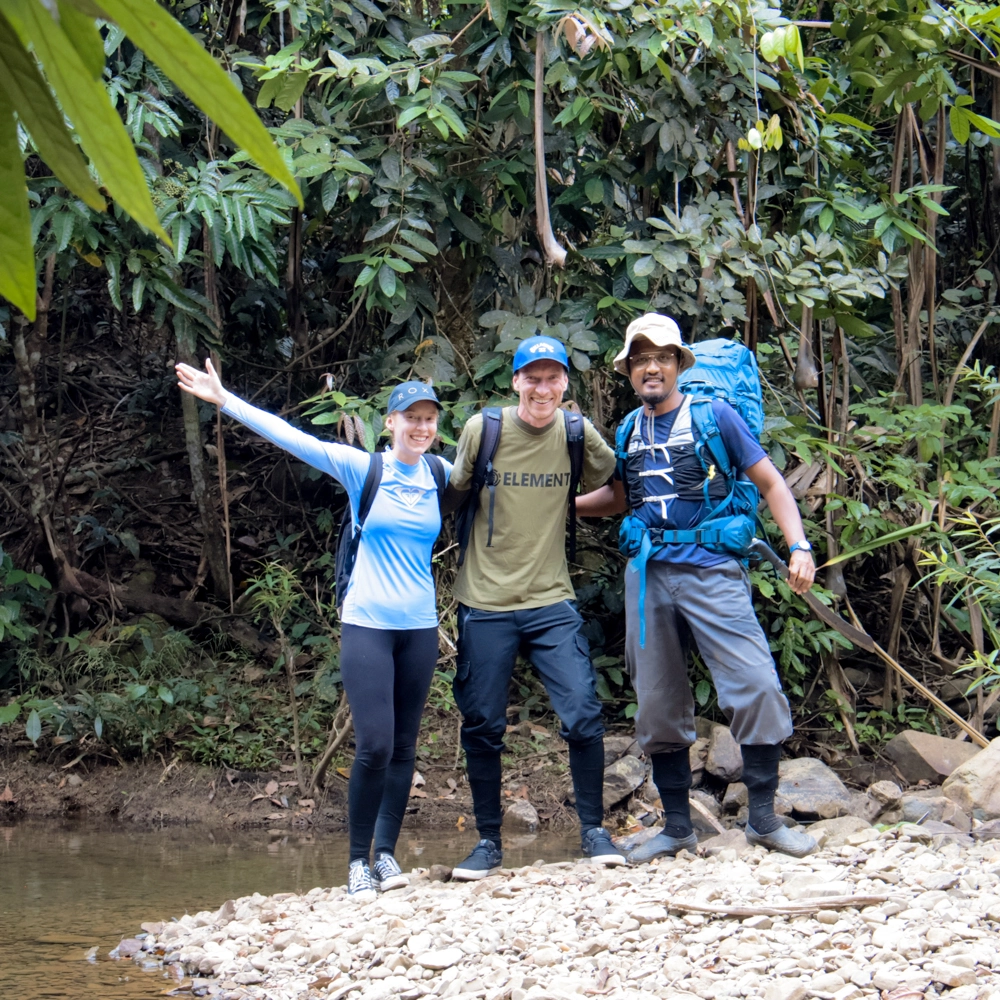Group of trekkers posing in the jungle, one raising a hand